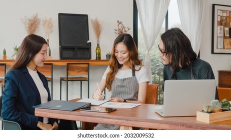 Cheerful Asian Small Business Owners Couple Meeting With Consultant Talking About Business Plan And Finance In Cafe. Young Japanese Agent Consider Signing Contract Insurance Together At Restaurant.