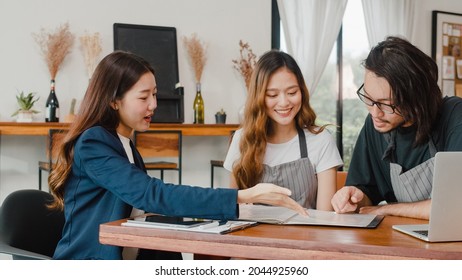 Cheerful Asian small business owners couple meeting with consultant talking about business plan and finance in cafe. Young Japanese agent consider signing contract insurance together at restaurant.