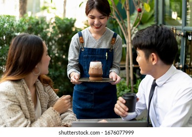 Cheerful Asian Thai Waitress Serving Ice Cold Coffee To Customers At Coffee Shop.