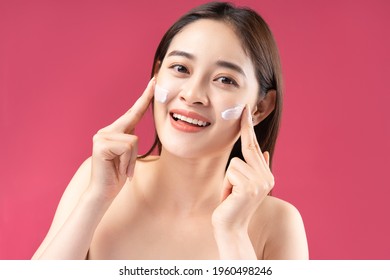 Cheerful Asian woman with beautiful skin using lotion