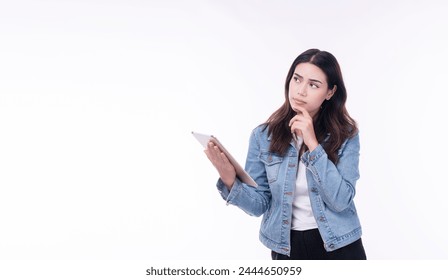 Cheerful asian woman denim jacket holding tablet thinking creative idea standing over isolated white background. Student young girl holding hand under chin education online tablet.Lifestyle technology - Powered by Shutterstock