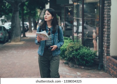 Cheerful Asian Woman With Trendy Look Searching Direction On Location Map In Town Carmel By The Sea California Usa. Happy Female Traveler Tourist Concept. Girl Backpacker Curious Walking On Street