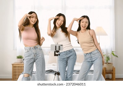 Cheerful Asian women dancing together to music while recording a short video on mobile phone for social media in bedroom at home. Imagination, creativity, Internet technology. influencer Live video - Powered by Shutterstock