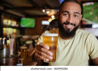 Cheerful Attractive African American Young Man Drinking Beer In Pub