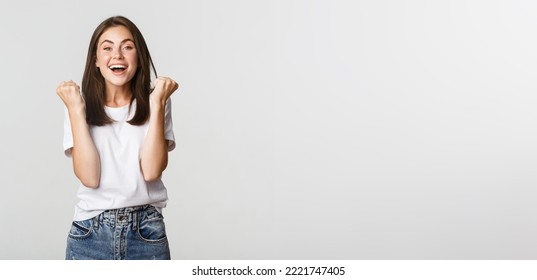 Cheerful attractive brunette girl fist pump and smiling with rejoice, winning. - Shutterstock ID 2221747405