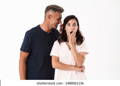 Cheerful attractive couple in love wearing casual outfit standing isolated over white background, man telling rumors - Shutterstock ID 1488061136