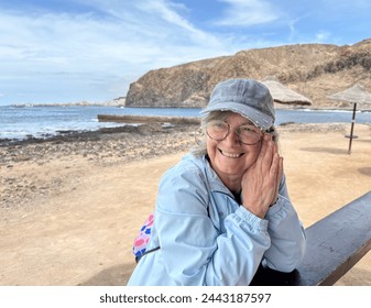 Cheerful attractive senior gray-haired woman at the beach looking away enjoying freedom and retirement, horizon over water on background - Powered by Shutterstock