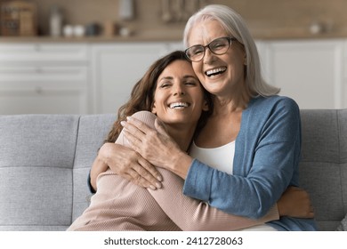 Cheerful attractive senior mom and happy adult daughter hugging at home with love, care, resting on couch together, smiling, laughing, talking, enjoying family relationship, bonding, motherhood - Powered by Shutterstock