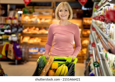 Cheerful Attractive Stylish Elderly Woman In Pink Shirt And Jeans Choosing Dairy Products At Supermarket, Female Pensioner Walking By Store With Trolley, Choosing Best Organic Food, Copy Space