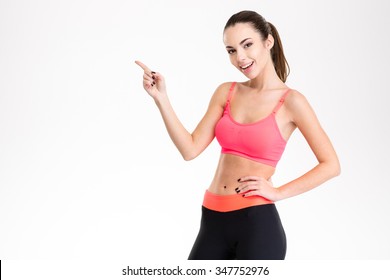 Cheerful Attractive Young Fitness Woman In Pink Top And Black Leggings Pointing Away Isolated Over White Background