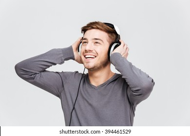 Cheerful Attractive Young Man In Headphones Listening To Music Over White Background