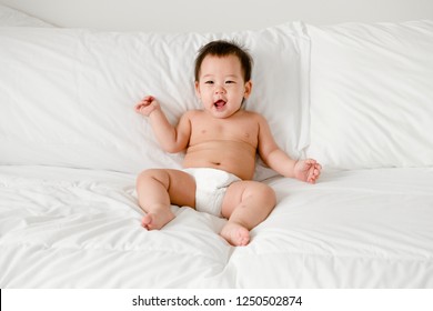 Cheerful Baby Sitting On The Bed