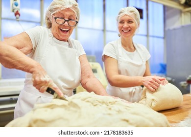Cheerful bakers cutting and kneading the dough in preparation for baking - Shutterstock ID 2178183635