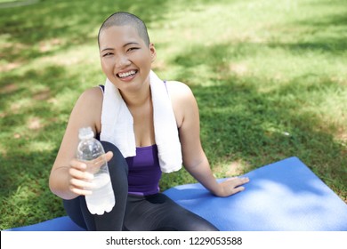 Cheerful Bald Young Vietnamese Woman Drinking Water After Exercising In Park