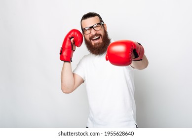 Cheerful bearded hipster man in casual punching with red boxing gloves. - Powered by Shutterstock