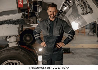 Cheerful Bearded Man Maintenance Technician Looking At Camera And Smiling While Standing Near Aircraft At Repair Station