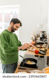 Cheerful bearded man pouring egg on frying pan while cooking near blurred fresh food on worktop - Shutterstock ID 2395465847