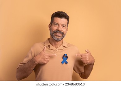 cheerful bearded man showing blue ribbon in beige studio background. prostate cancer, awareness concept. - Powered by Shutterstock