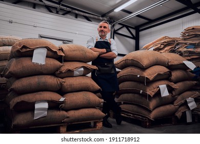 Cheerful bearded man wearing apron posing standing confidently with arms crossed near coffee bags. Full length. - Powered by Shutterstock