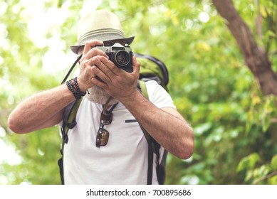 Cheerful bearded senior tourist taking photos of nature - Powered by Shutterstock