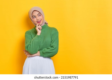 Cheerful beautiful Asian woman in green sweater looking at copy space, creating new idea solution isolated over yellow background - Powered by Shutterstock