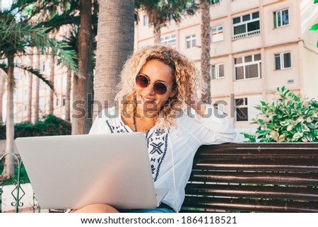 Cheerful beautiful lady work outdoor at the park with laptop computer sitting ona bench enjoying nature and freedom from office - concept of smart working and online job everywhere with connection Zdjęcia stock © 