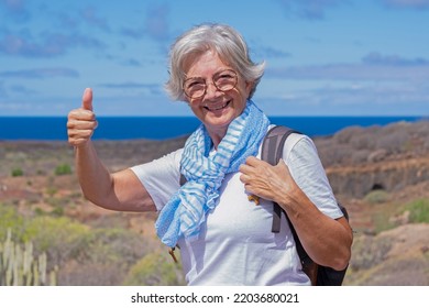 Cheerful Beautiful Senior Woman With Thumb Up While Enjoys Freedom And Excursion Close To The Sea - Horizon Over Water