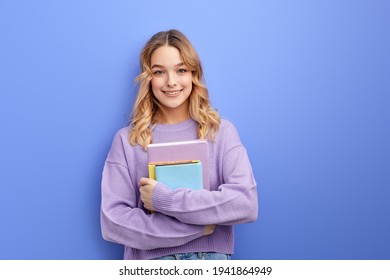 Cheerful beautiful teen student girl hold books isolated on pastel blue background studio portrait