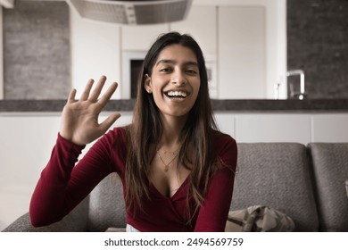 Cheerful beautiful young Indian blogger woman waving hand hello at camera, speaking with toothy smile, talking on online meeting with blog audience on video call, broadcasting on Internet - Powered by Shutterstock