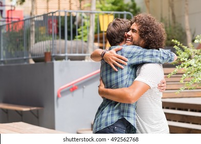 Cheerful best friends embracing each other outside coffee shop. Two young multiethnic guys hugging each other. Happy smiling best friends meeting each other after a long time with a hug. - Shutterstock ID 492562768