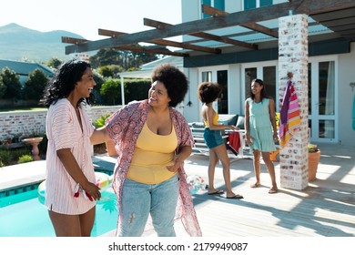 Cheerful Biracial Female Friends Talking While Spending Leisure Time At Poolside During Summer. Hangout, Unaltered, Friendship, Togetherness, Social Gathering, Enjoyment And Weekend Activities.