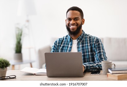 Cheerful Black Businessman Sitting At Laptop Smiling To Camera Working Online On Computer In Modern Office. Entrepreneurship And Own Business. Successful Career Concept. Selective Focus