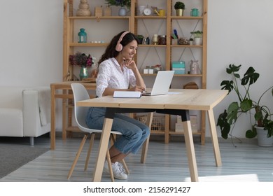 Cheerful Black College Student In Earphones Attending Virtual Class, Writing Notes, Watching Webinar On Internet, Studying Online. African Worker In Headphones Talking To Customer On Video Call