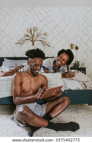 Cheerful black couple using digital devices