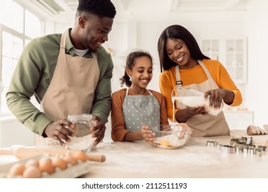 Cheerful Black Family Baking Cookies, Adding Milk To Dough Mixing Ingredients In A Bowl Cooking Together In Modern Kitchen Indoor On Weekend. Pastry Recipes Concept