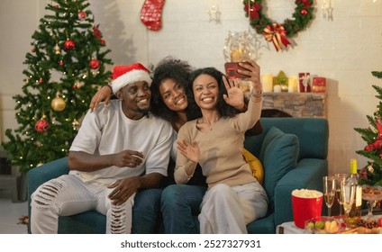 Cheerful black family captures joyful moment with selfie and video call with friends and relatives during their Christmas celebration, surrounded by festive decorations and a beautifully adorned tree - Powered by Shutterstock