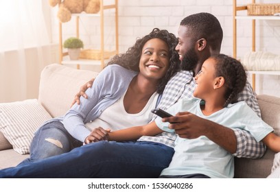 Cheerful Black Family Having Fun Together Watching TV Show And Switching Channels With Remote Controller