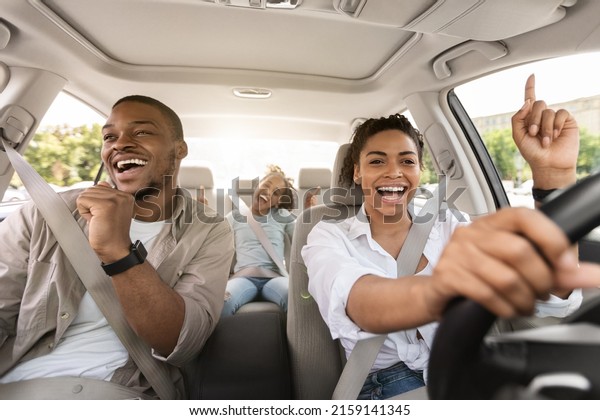 Cheerful Black Family Singing\
Riding New Car Having Fun Enjoying Road Trip On Vacation. Parents\
And Daughter Traveling By Automobile In Summer. Selective\
Focus