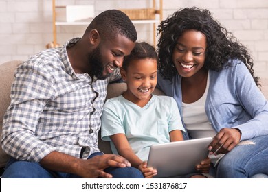 Cheerful Black Family Using Digital Tablet Together At Home, Watching Funny Videos.