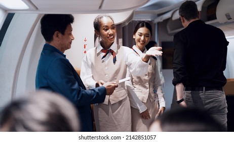 Cheerful black fight attendant and cabin crew assistant checking travel tickets and informing seat to passengers before departure taking care of passengers on airplane working with service mind        - Shutterstock ID 2142851057