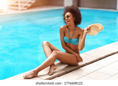 Cheerful black girl in sexy swimsuit having great time by swimming pool outdoors