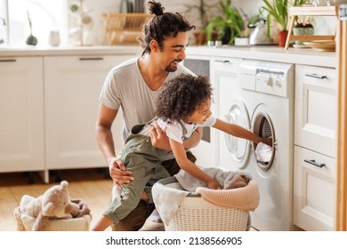 Cheerful Black Kid Boy Helping Father At Linen In Basket While Doing Laundry Near Washing Machine In Flight Kitchen In Weekend At Home  