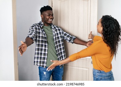 Cheerful Black Man And Lady Meeting Stretching Hands For An Embrace Standing Near Opened Entry Door At Home. Female And Male. Friendship Concept. Selective Focus