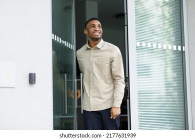 A Cheerful Black Man Leaves The House, Opening The Glass Door.