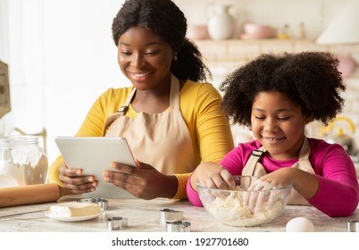 Cheerful Black Mom And Cute Little Child Using Digital Tablet In Kitchen While Baking, Checking Cookies Recipe Online, African American Family Enjoying Preparing Homemade Pastry, Closeup Shot - Powered by Shutterstock