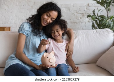 Cheerful Black Mom And Girl Putting Coin Into Pink Piggy Bank. Happy Loving Mother Teaching Little Daughter Kid To Save Money, Motivate For Accounting, Investment, Planning Future. Family Finance.