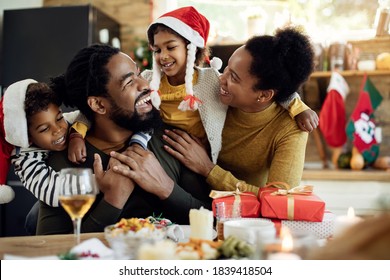 Cheerful Black Parents And Their Kids Having Fun While Spending Christmas Together At Home. 