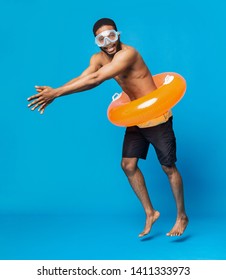 Cheerful Black Shirtless Man In Swim Goggles And Inflatable Ring Having Fun, Diving On Blue Studio Background, Free Space