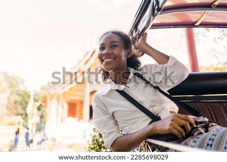 cheerful black tourist girl head out from tuk tuk ride. happy solo traveler girl holding steel bar enjoying air flow on tuk. african american young tourist using bar headout for air on riding.