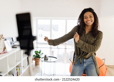 Cheerful Black Woman Dancing At Camera Filming Video Using Cell Phone On Tripod At Home, Creating Trendy Content On Mobile App To Share On Social Media, Selective Focus On Excited Millennial Lady